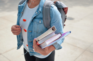 Etudiante porte des livres de cours dans les bras