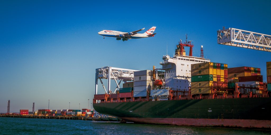 avion qui passe au dessus d'un bateau avec des containers