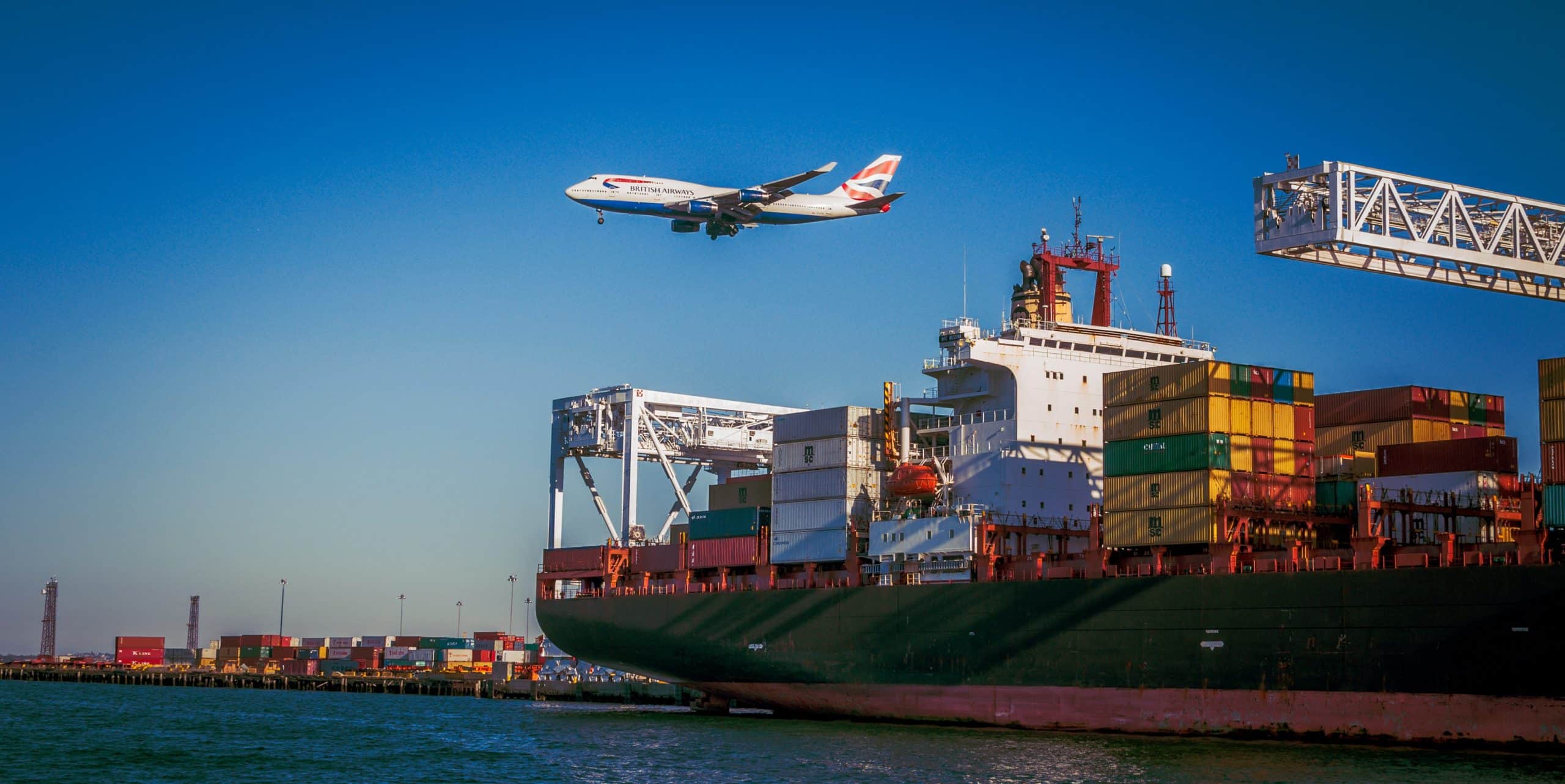 avion qui passe au dessus d'un bateau avec des containers